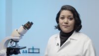 Girl in white lab coat with microscope.