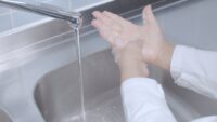 Washing hands in laboratory with disinfectant soap wearing a lab coat.