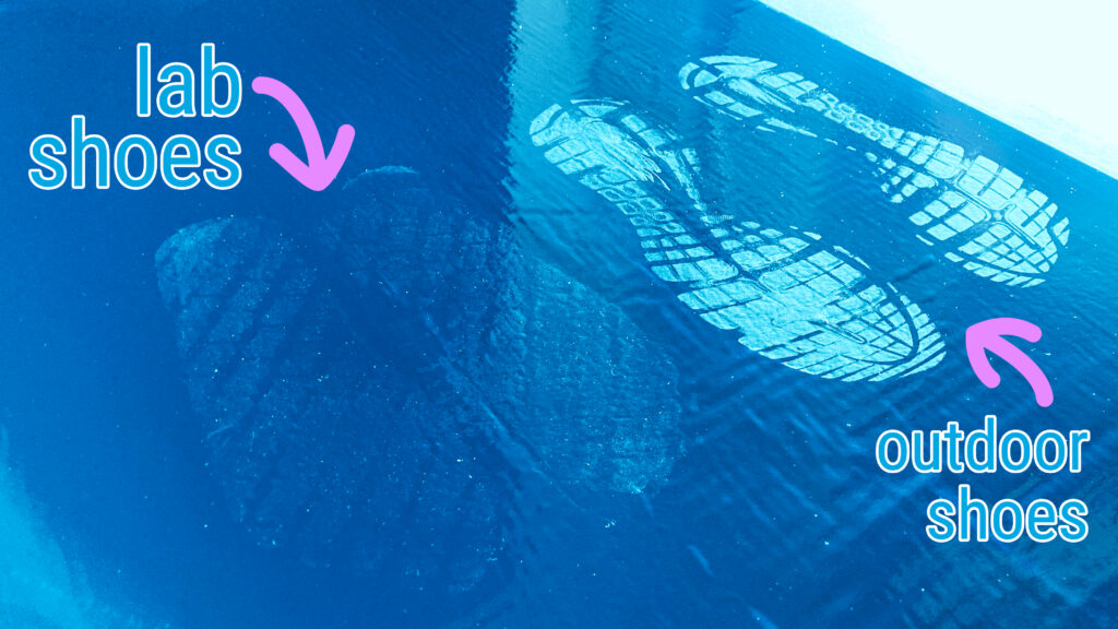 Bright blue sticky mat before the entrance of cell culture laboratory with footprints from outdoor shoes and lab slippers in comparison.