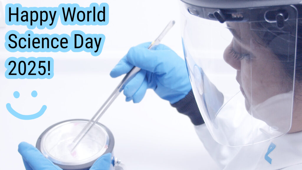 A person in the lab handling liquid nitrogen in a dewar, wearing protective gear, such as face shield, a white lab coat and using forceps.