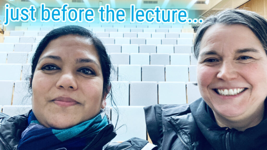 Asmita Banerjee and Adelheid Weidinger wearing winter clothes in the empty Audimax of Hochschule Campus Wien.