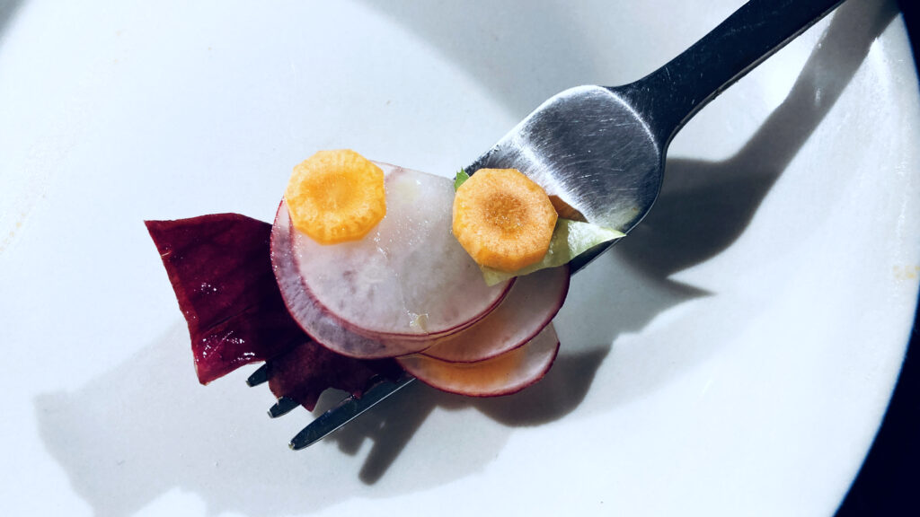 two slices of carrot, some radish and some radicchio on a fork.
